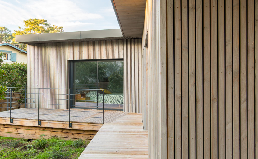 Brise-soleil en bois filtrant la lumière devant une baie vitrée aluminium grand format